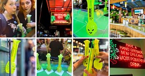 women drinking from tall souvenir cups, Tropical Isle sign, Hand Grenade cocktail, New Orleans' most powerful drink